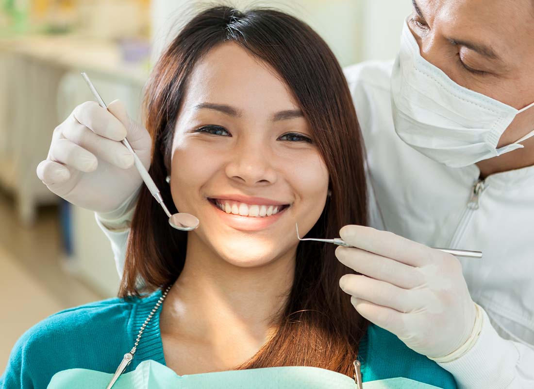 Individual Dental Insurance - Close-up Portrait of a Young Smiling Woman While Waiting in Dentist Chair for a Teeth Cleaning by Dentist