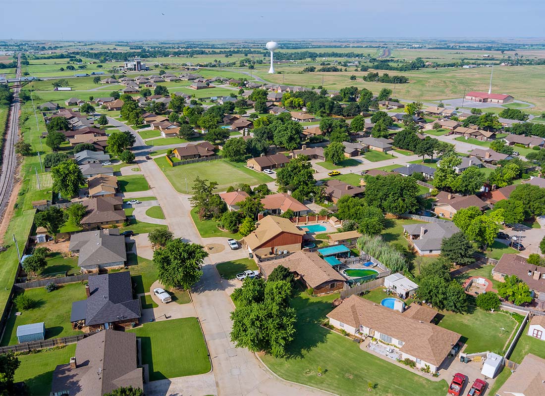 About Our Agency - Aerial View of Homes with Green Lawns and Trees in the Suburbs on a Sunny Day in Oklahoma