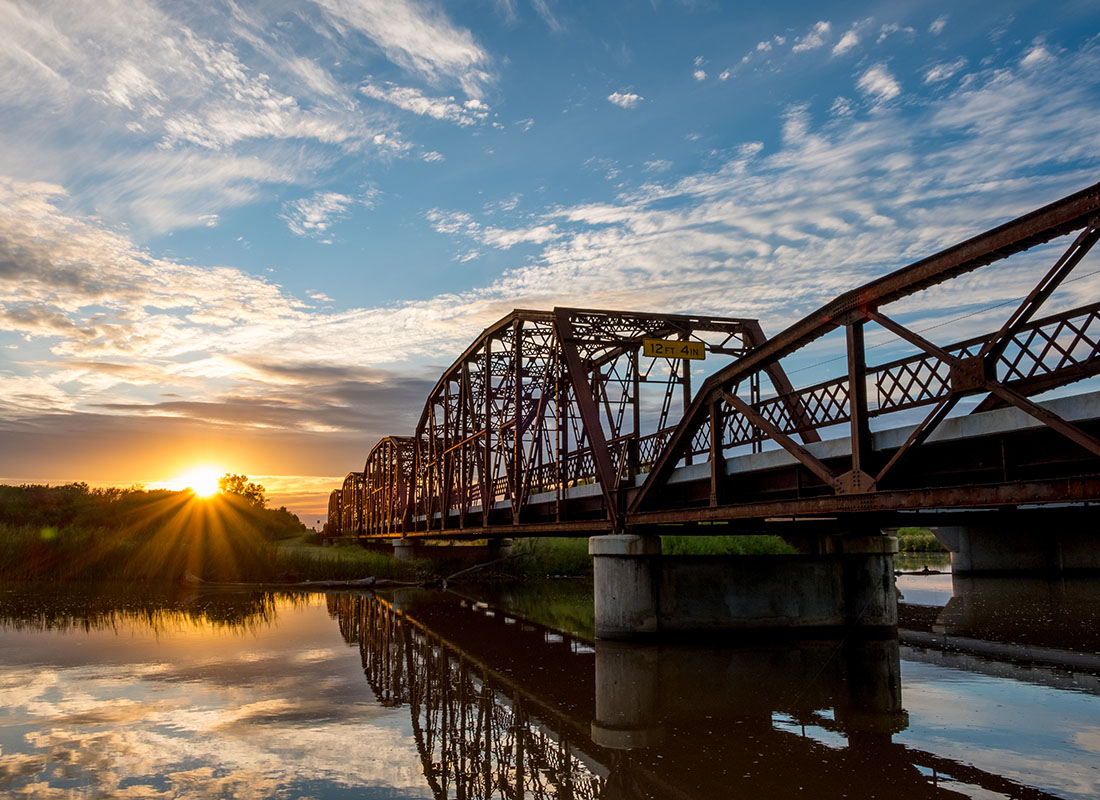 Contact - Scenic View of an Old Steel Bridge Across the River at Sunset with a Cloudy Sky